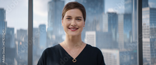 Close Up Beautiful Portrait of Caucasian Businesswoman Posing Next to Window in Big City Office with Skyscrapers. Female CEO Smiling, Looking At Camera. Successful Business Manager. Free Download Close Up Beautiful Portrait of Caucasian Businesswoman Posing Next to Window in Big City Office with Skyscrapers. Female CEO Smiling, Looking At Camera. Successful Business Manager. - GFXLoad