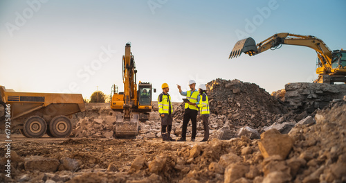 Construction Site With Excavators on Sunny Day: Diverse Team Of Male And Female Real Estate Developers Discussing Project. Engineer, Architect, Investor Talking About Apartment Building, Using Tablet