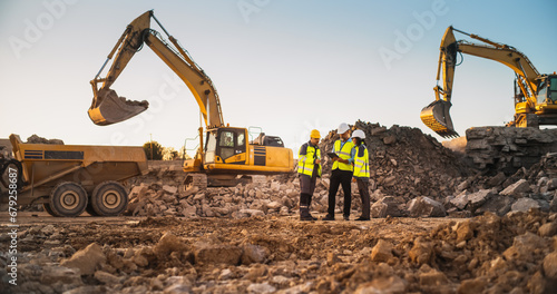 Construction Site With Excavators on Sunny Day: Diverse Team Of Male And Female Real Estate Developers Discussing Project. Engineer, Architect, Inspector Talking About Apartment Complex, Using Tablet photo