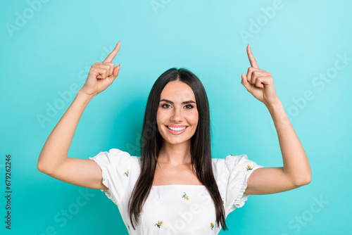 Photo of young nice woman model wearing white trendy crop top direct fingers up useful tips promoting isolated on cyan color background photo