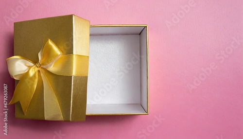 Fotografie open gift box and gold bow on pink background with copy space for your message,