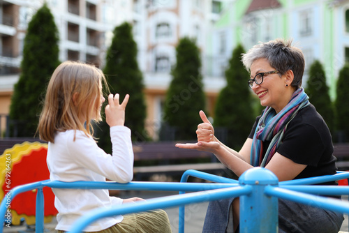 A young girl child and happy woman proficient in sign language communicates joyfully, fostering connections in the city.