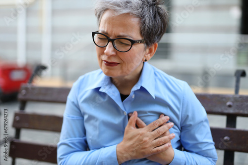 Senior woman, experiencing chest pain, signifies a potential cardiac issue, invoking concern for her health. photo
