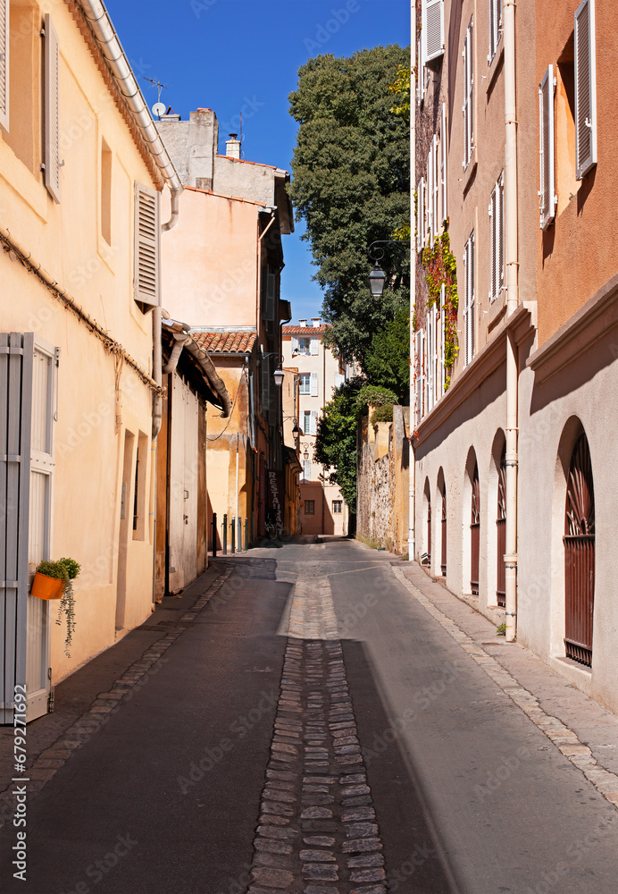 Ruelle d'une quartier populaire du centre ville du sud de la France avec volets en bois et murs en crépis ocres.