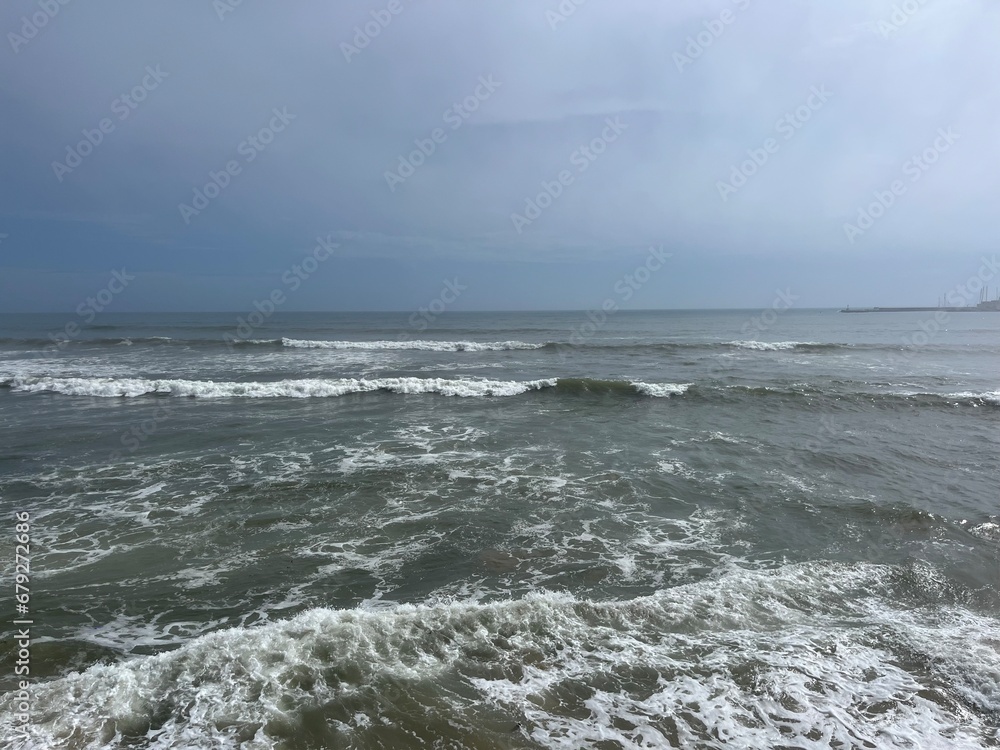 Rainy cloudy sky at the sea, waves sea horizon, gray seascape, foam at the water