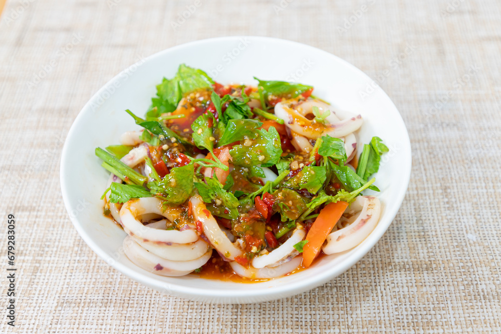Squid salad cut into circles Thai style squid salad, sour, spicy, delicious. Squid salad on a white plate.