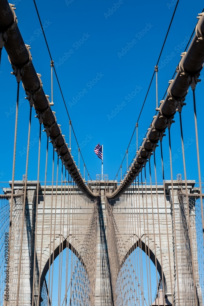 Obraz premium American flag on the Brooklyn Bridge with a clear blue sky in the background