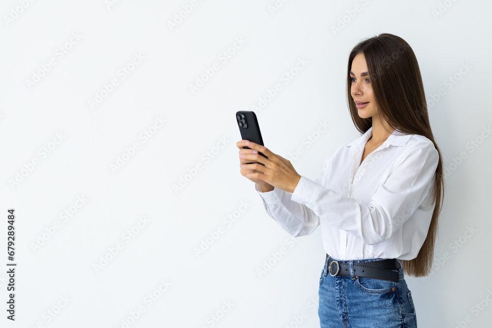 Happy b woman holding smartphone in hands and looking at the camera over white background Happy b woman holding smartphone in hands and looking at the camera over white background