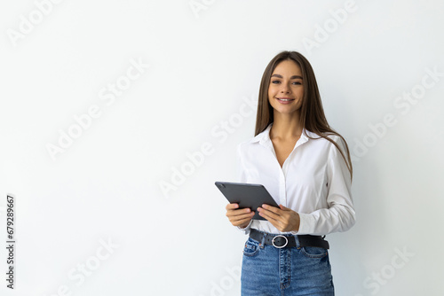 Young woman smiling and holding digital tablet, standing over white background