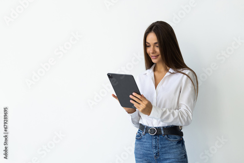 Portrait of young smiling woman standing with tablet near concrete wall. Concept of planning.
