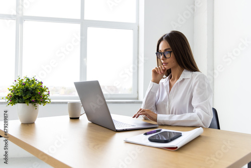 Attractive businesswoman working on laptop in her workstation. © F8  \ Suport Ukraine