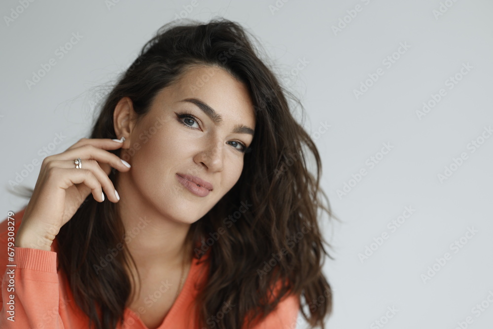 Beautiful woman of 30 years old sitting on chair, white background. Portrait of brunette girl smile. Orange sweater and light jeans. Woman barefeet, thoughtful. Beautiful woman of 30 years old sitting on chair, white background. Portrait of brunette girl smile. Orange sweater and light jeans. Woman barefeet, thoughtful.