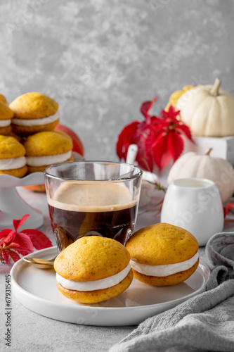 Pumpkin sandwich cookies with cream cheese on a gray concrete bsckground. Spicy autumn dessert. Copy space.