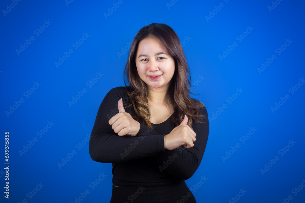 Fototapeta premium Young Asian woman wearing casual black T-shirt with happy smiling face and giving thumbs up