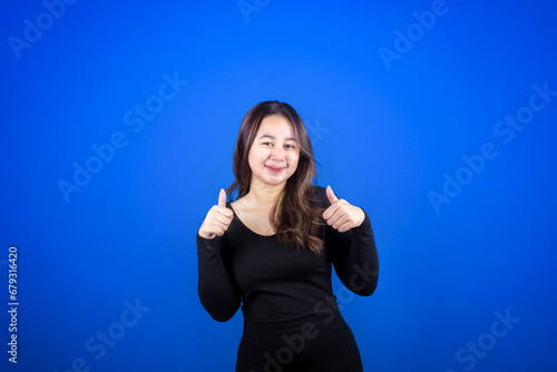Young Asian woman wearing casual black T-shirt with happy smiling face and giving thumbs up