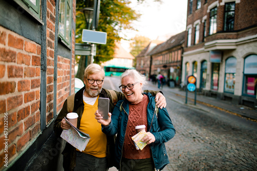 Senior couple holding smartphone on vacation in city photo