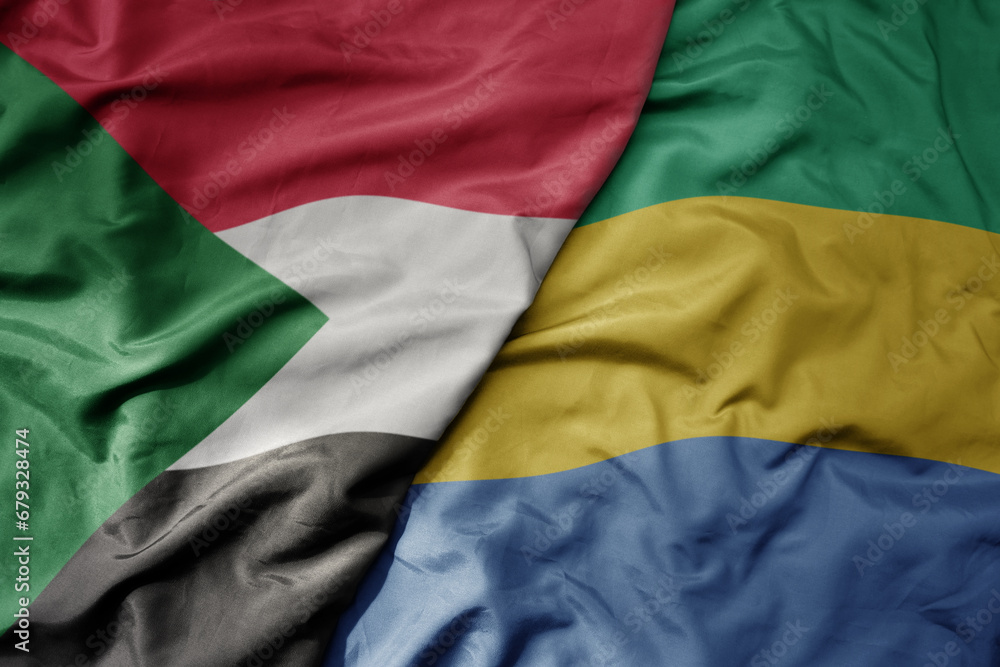 big waving national colorful flag of sudan and national flag of gabon .