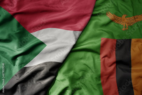 big waving national colorful flag of sudan and national flag of zambia .