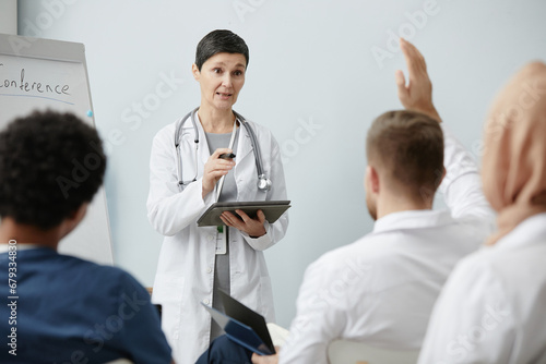 Waist up portrait of mature female doctor speaking to audience at medical conference  copy space