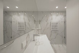 Modern minimalist white bathroom interior design with marble style tiles and white taps, vase and wall heater