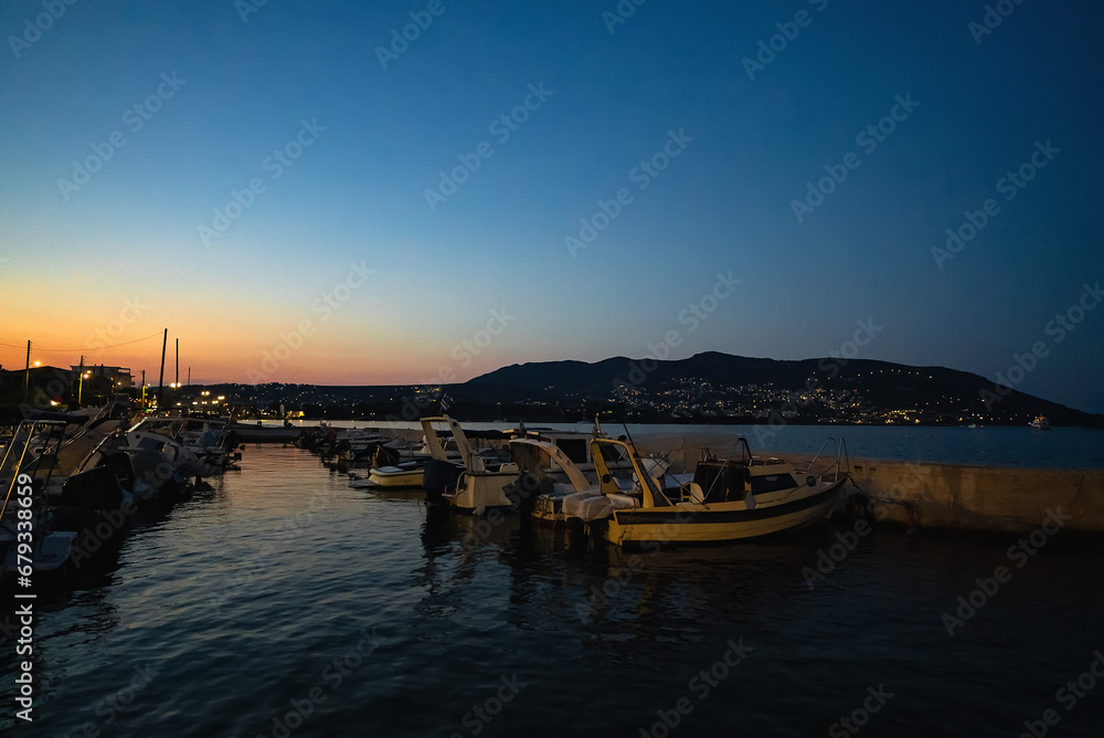 Boats in the harbor in the city of Porto Rafti in Greece at sunset.