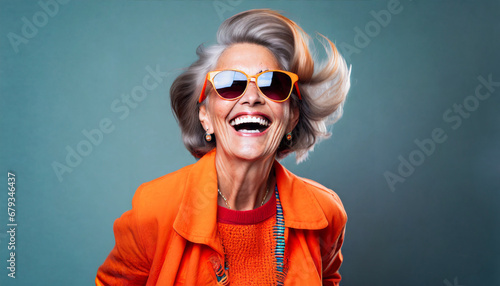 happy senior woman in colorful orange outfit cool sunglasses laughing and having fun in fashion studio