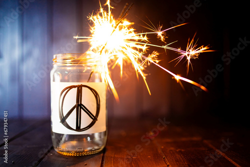 Hope for peace, still life with glass jar with peace symbol and burning sparkler. Background with copy space.  photo