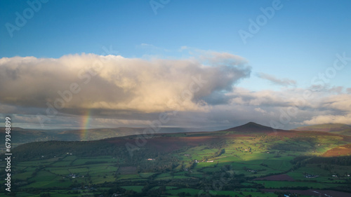 Sugar Loaf mountain near Abergavenny in the Brecon Beacons Black Mountains national park. Rainbow and clouds over rugged natural beauty Mynydd Pen-y-fâl in Bannau Brycheiniog South Wales photo