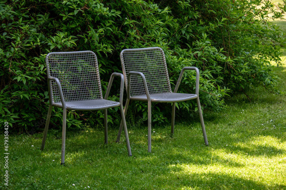 Fototapeta premium Metal chairs in spring garden. Metal garden furniture for picnics and birdwatching