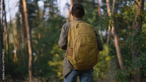 Wallpaper Mural woman hiker in park. girl tourist with yellow backpack walk through forest park sunset sunlight. summer outdoor travel tourism concept. hiker walk in pine forest in wild park. feminism concept Torontodigital.ca