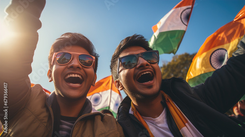Two young men celebrate India's bank holidays with joy and pride, standing out in front of the majestic national flag flying in the background.