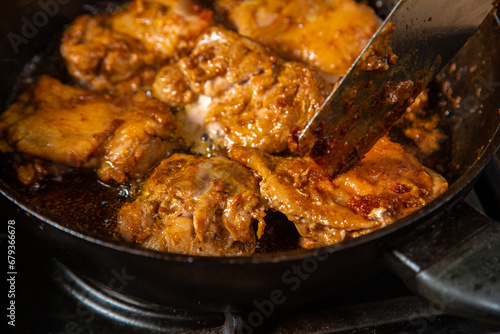 Turn the chicken in spices in a frying pan with an iron spatula.