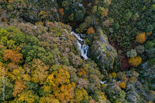 drone aerial view of a mountain with an autumn deciduous forest and a waterfall