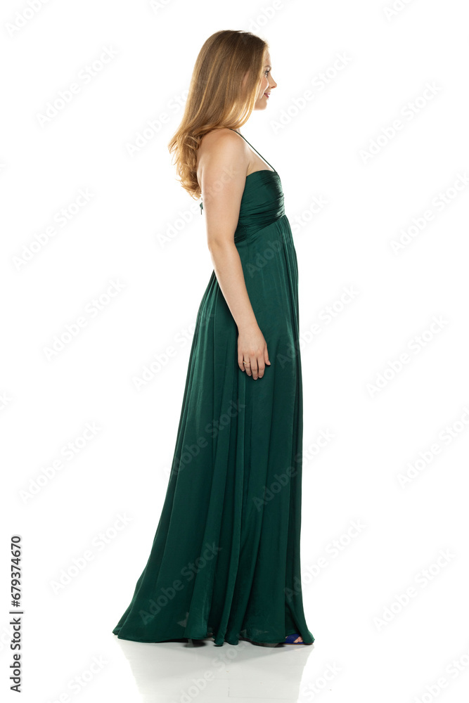 Full body side view portrait of elegant lovely blond lady  posing isolated on white background in green long dress