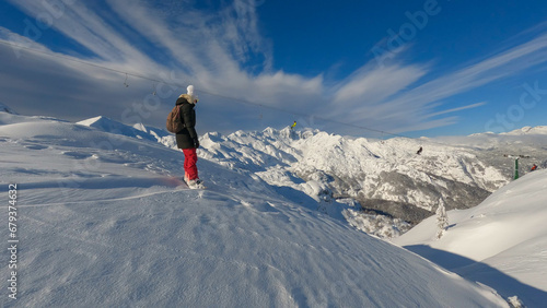 Snowboarder stopped on top of untracked slope before riding down in fresh snow