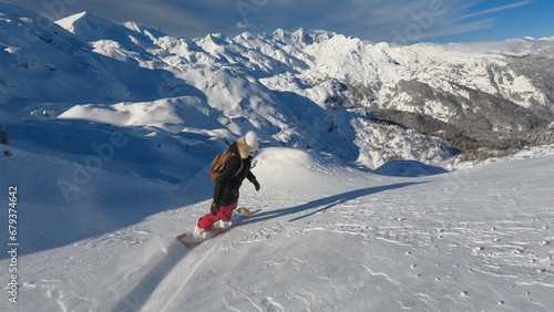 Adventurous woman freeride snowboarding on fresh powder snow in the Julian Alps