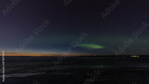 Green aurora borealis over a frozen lake in Tampere, Finland