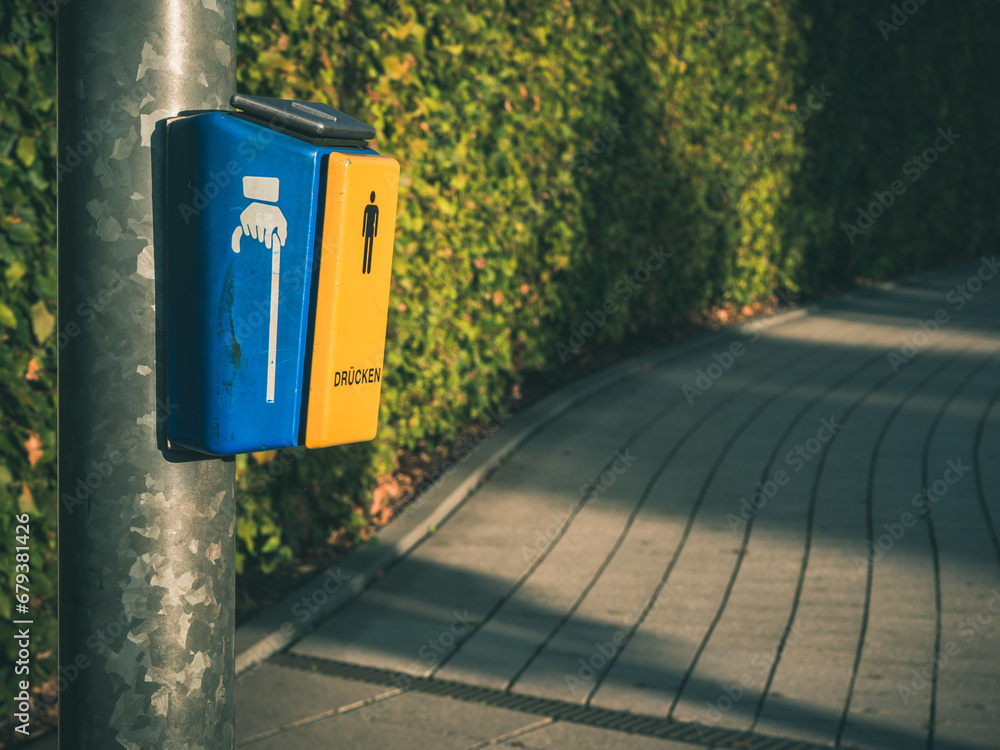 Yellow button for disabled pedestrians with the inscription PRESS on a pedestrian crossing. Selective focus