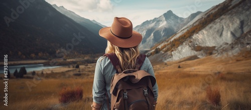 Portrait young woman wearing a backpack at field with mountain background. AI generated