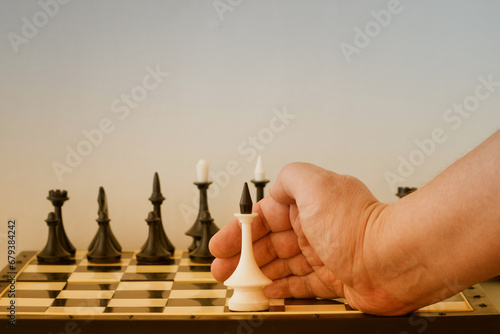A person's hand defends one white king from black pieces. Protection and care, sheltering the weak and vulnerable, intervention of external forces. photo