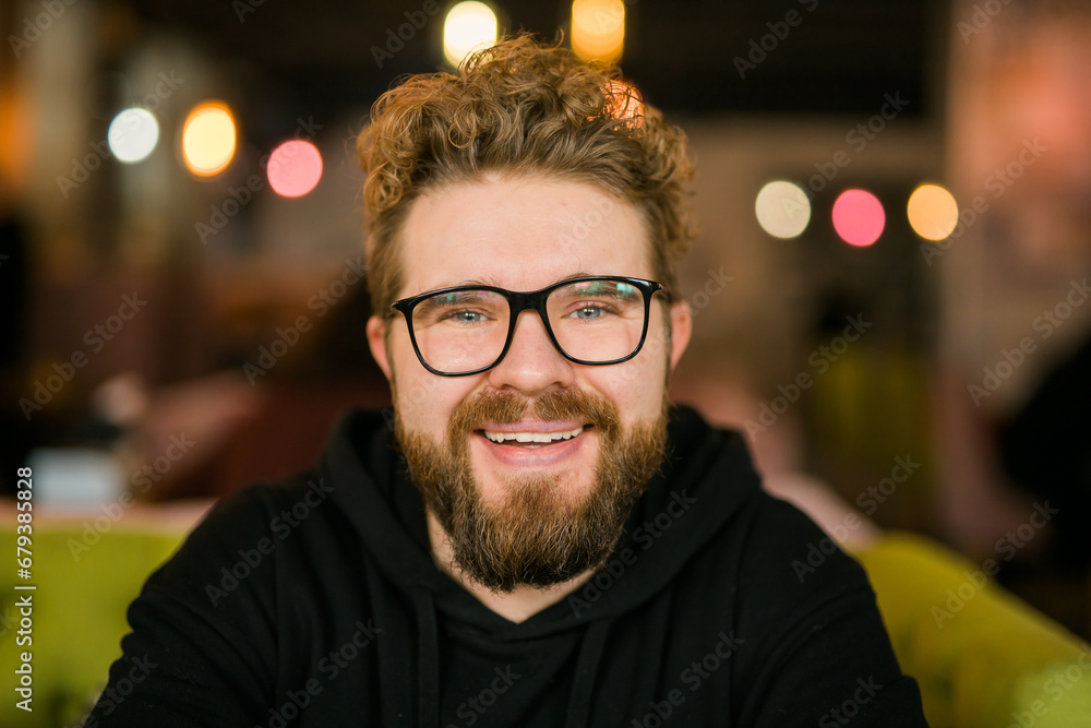 Close up portrait of young handsome freelance man wearing stylish eyeglasses on cafe. Happy confident student looking at camera, education and online work concept. Millennial generation and Gen Y Close up portrait of young handsome freelance man wearing stylish eyeglasses on cafe. Happy confident student looking at camera, education and online work concept. Millennial generation and Gen Y