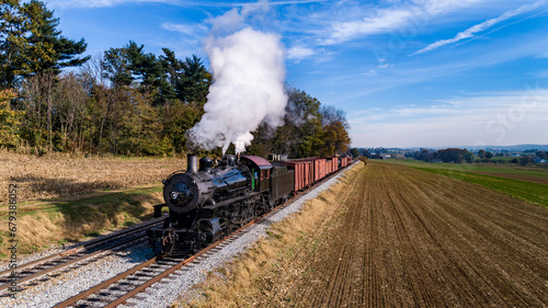 An Aerial View of an Antique Steam Freight Passenger Train Blowing Smoke as it Slowly Travels on an Autumn Day