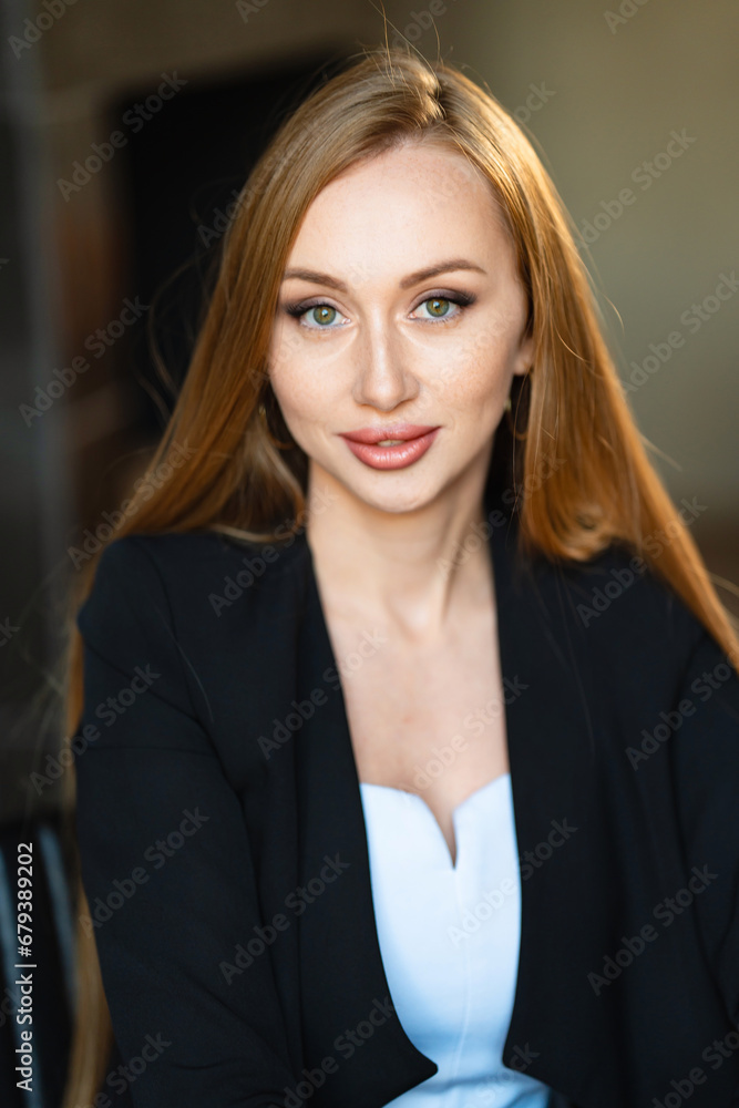 Fototapeta premium portrait of a Beautiful businesswoman with long red hair in black business suit.