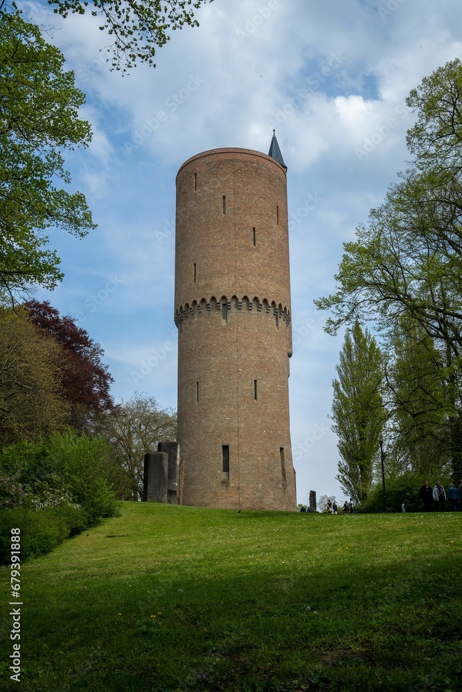 the tower is standing above a grassy field with trees and bushes