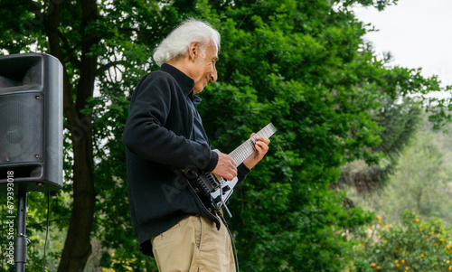 Senior man playing electric guitar during a concert in the park