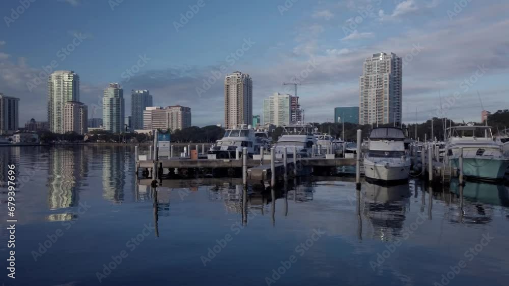 Looking west from Yacht Basin Marina in St. Petersburg, Florida and Park in the early morning sun. Boats and skyline buildings in the background. Blue calm water with reflections of buildings. Looking west from Yacht Basin Marina in St. Petersburg, Florida and Park in the early morning sun. Boats and skyline buildings in the background. Blue calm water with reflections of buildings.