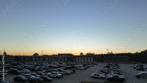 Busy outdoor parking lot with a variety of vehicles parked in front of a school