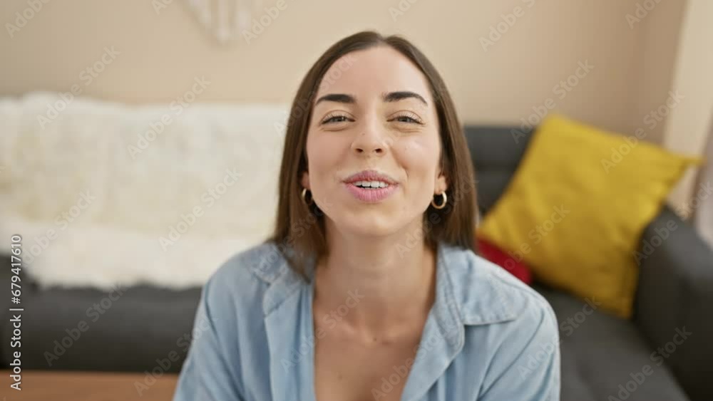 Cheerful young hispanic woman enjoying home fun, confidently sitting on sofa, inflating mouth with air - a laughing, attractive portrait in living room interior. Cheerful young hispanic woman enjoying home fun, confidently sitting on sofa, inflating mouth with air - a laughing, attractive portrait in living room interior.