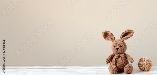Cute knitted toy rabbit on white wood table and pastel color wall background with copy space. Easter concept. photo