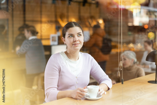 Relaxed woman drinking hot coffee thinking in cozy cafe